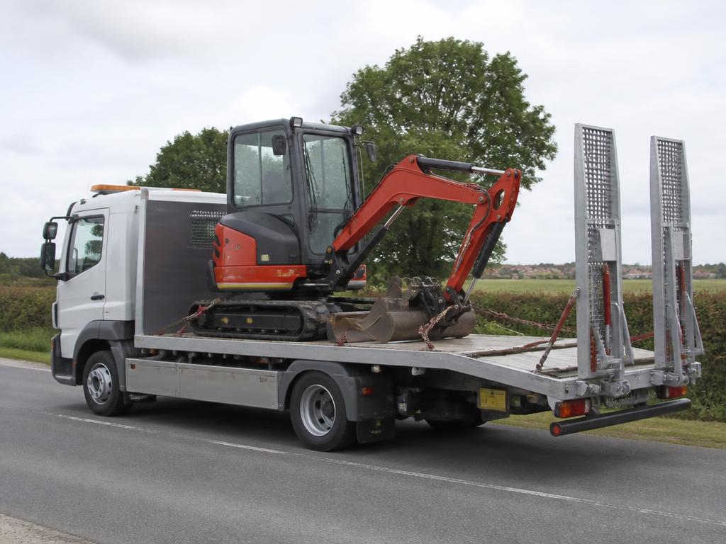 Camion plateau transportant une mini-pelle arrimée